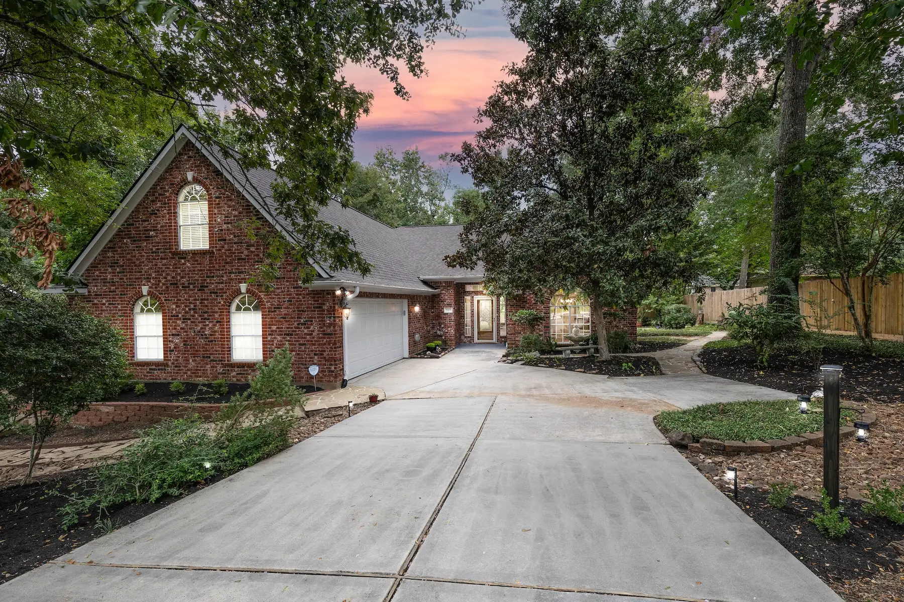 Front exterior at dusk — brick home with mature trees