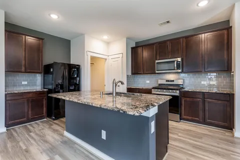 Kitchen with granite island, dark cabinetry, and stainless appliances