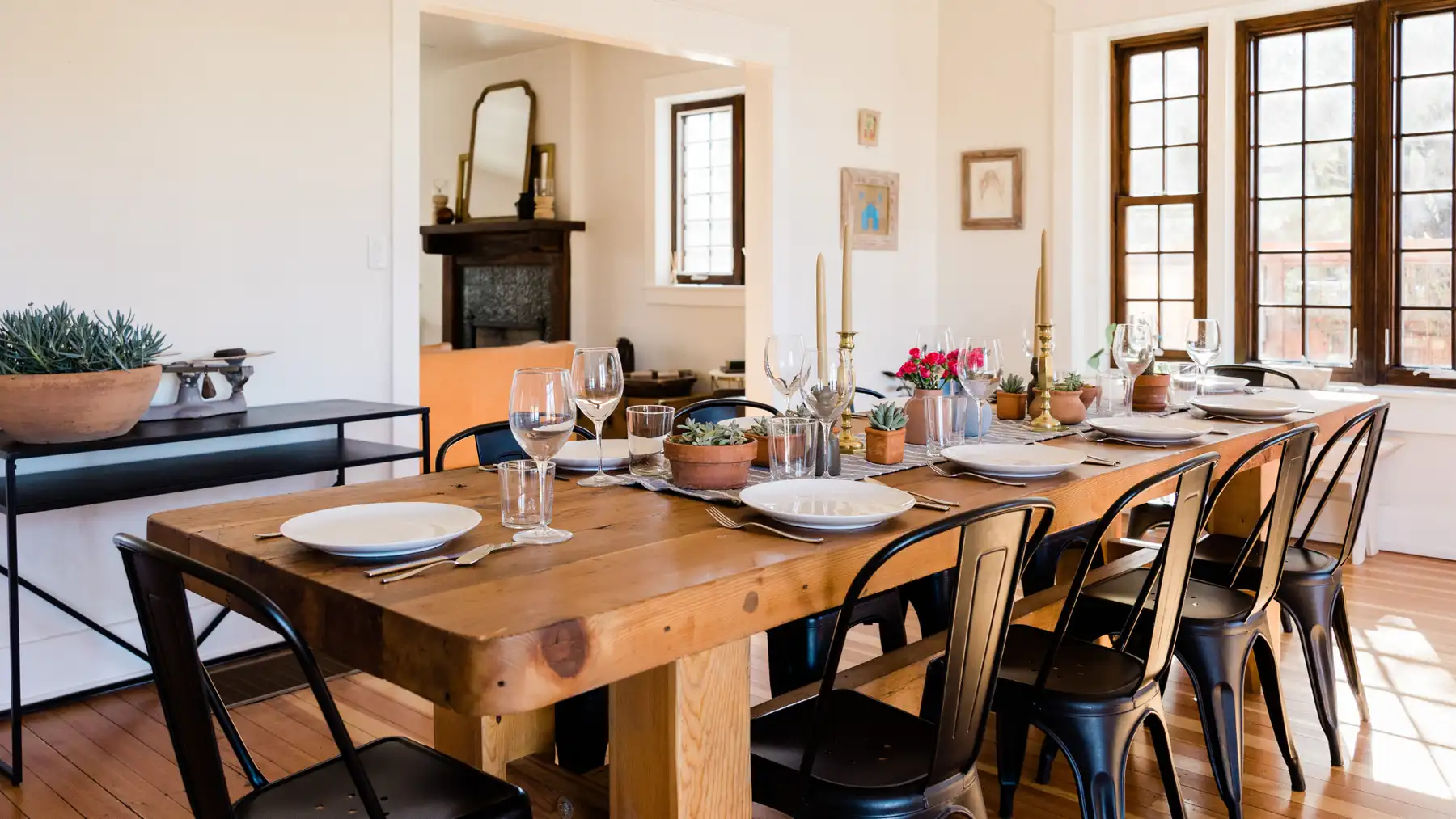 A long wooden table set for a family dinner, warm light through the windows