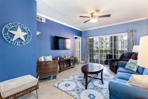 Light, coastal living room with crown molding and balcony access