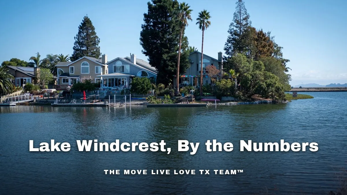 Waterfront homes with docks and tall trees along a calm blue lake on a sunny day