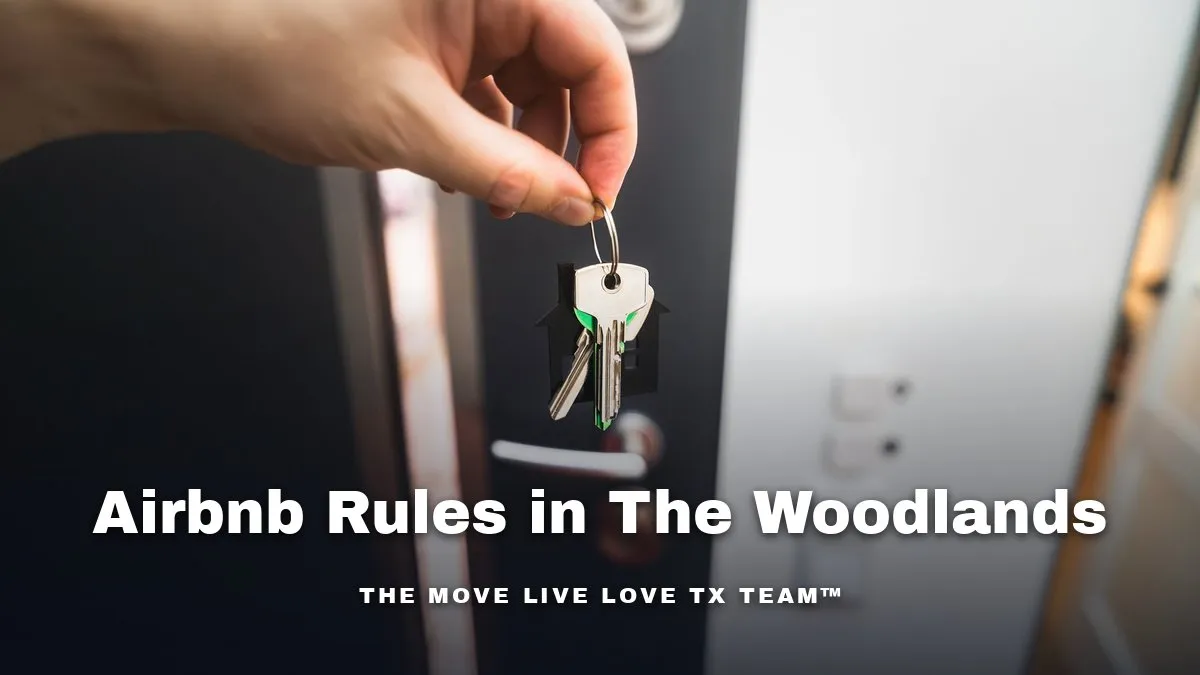 A hand holding a set of house keys in front of an open front door